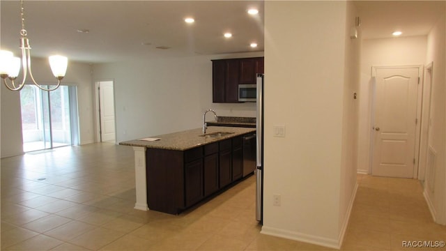 kitchen featuring sink, an inviting chandelier, light stone counters, a kitchen island with sink, and appliances with stainless steel finishes