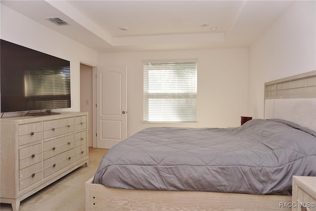 bedroom with a raised ceiling and light carpet