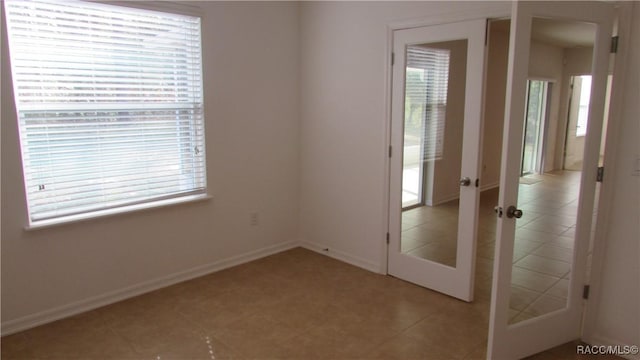 tiled spare room featuring french doors