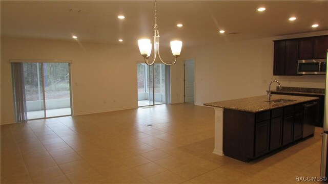 kitchen featuring light stone countertops, a kitchen island with sink, plenty of natural light, and sink