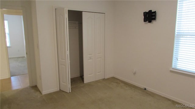 unfurnished bedroom with light carpet and a closet