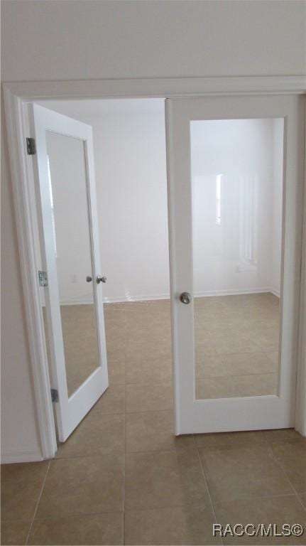 hall featuring tile patterned flooring and french doors