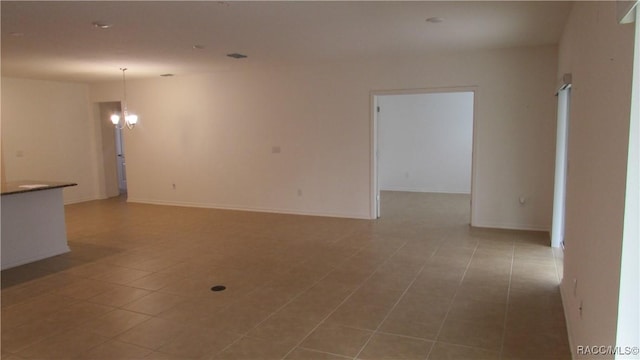 tiled empty room with an inviting chandelier