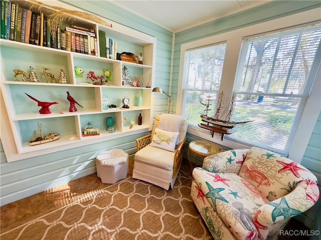 living area with wooden walls, crown molding, and carpet floors