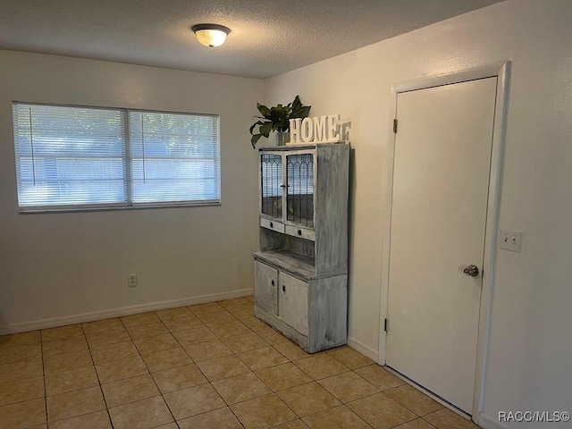 interior space featuring light tile patterned flooring and a textured ceiling