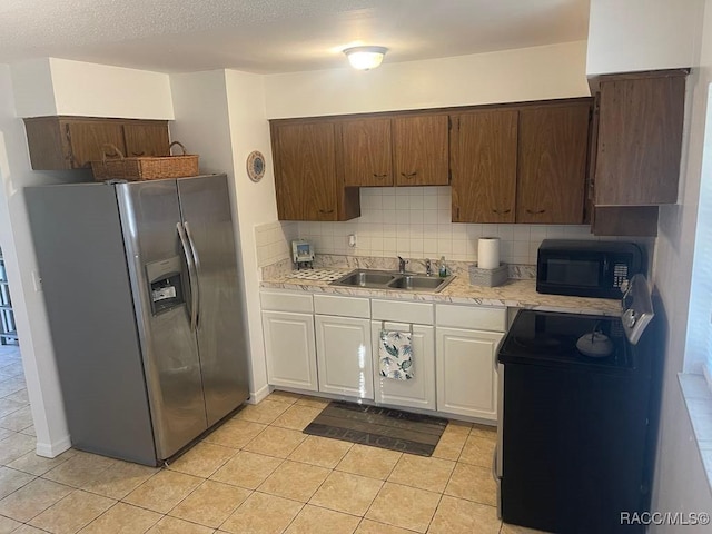 kitchen with sink, white cabinets, decorative backsplash, light tile patterned floors, and black appliances