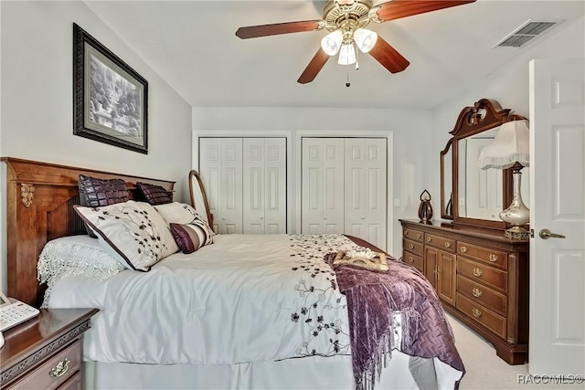 carpeted bedroom with two closets and ceiling fan