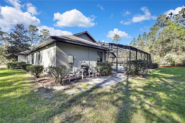 rear view of property with glass enclosure, a patio area, and a yard