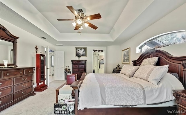 carpeted bedroom with ceiling fan and a raised ceiling