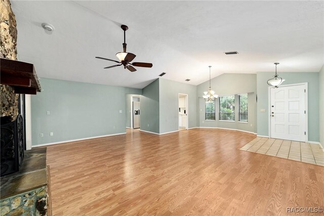 220 E Liberty St, Hernando, FL 34442 - unfurnished living room with vaulted ceiling, ceiling fan, a fireplace with raised hearth, a chandelier, and wood finished floors