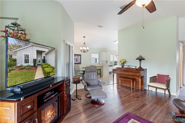 living room with hardwood / wood-style flooring and ceiling fan with notable chandelier