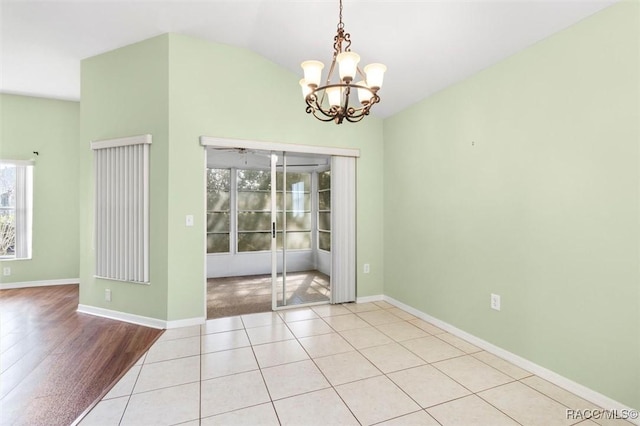 unfurnished dining area featuring vaulted ceiling, light tile patterned floors, a chandelier, and baseboards