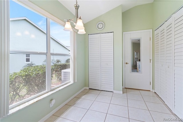 unfurnished dining area featuring a chandelier, lofted ceiling, light tile patterned flooring, and baseboards