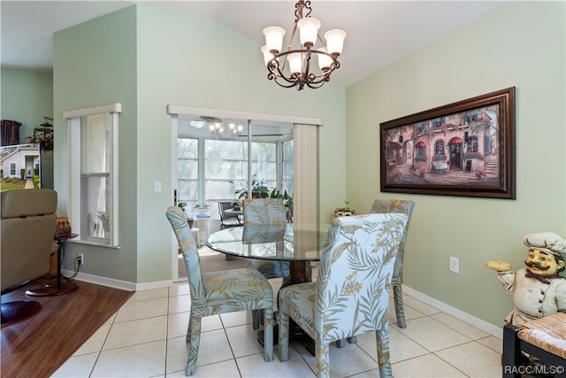 dining space with light hardwood / wood-style flooring, a chandelier, and vaulted ceiling