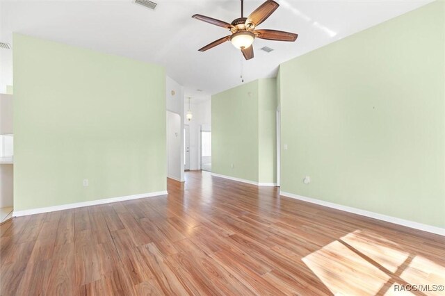 living room featuring ceiling fan with notable chandelier, light hardwood / wood-style floors, and vaulted ceiling