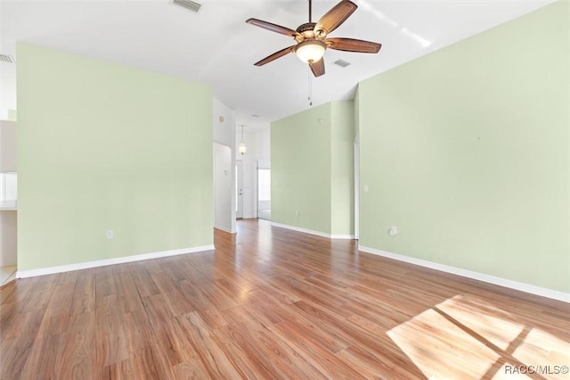 spare room featuring a ceiling fan, visible vents, light wood-style flooring, and baseboards