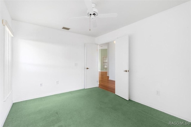 carpeted empty room with ceiling fan and visible vents