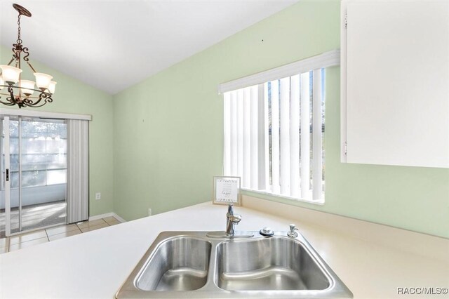 kitchen with white cabinets, vaulted ceiling, sink, decorative light fixtures, and a chandelier