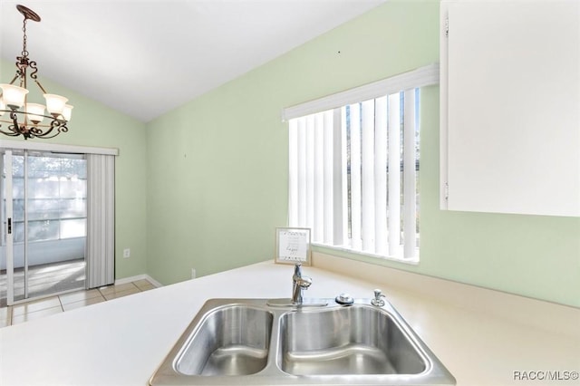 kitchen with lofted ceiling, decorative light fixtures, light countertops, a chandelier, and a sink