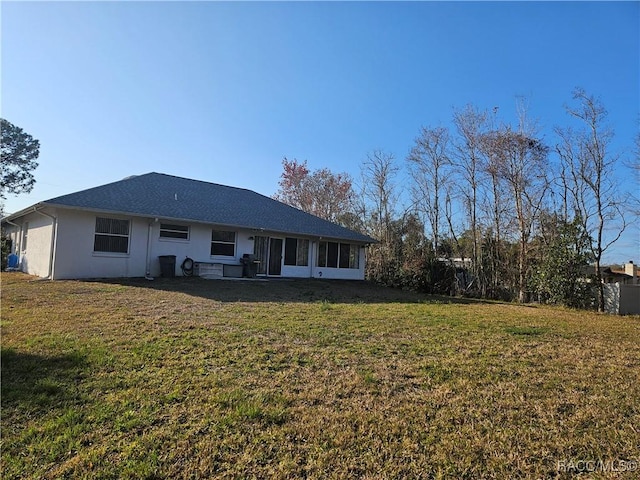 rear view of property featuring a sunroom and a lawn