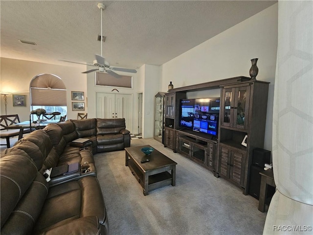 carpeted living room featuring ceiling fan and a textured ceiling