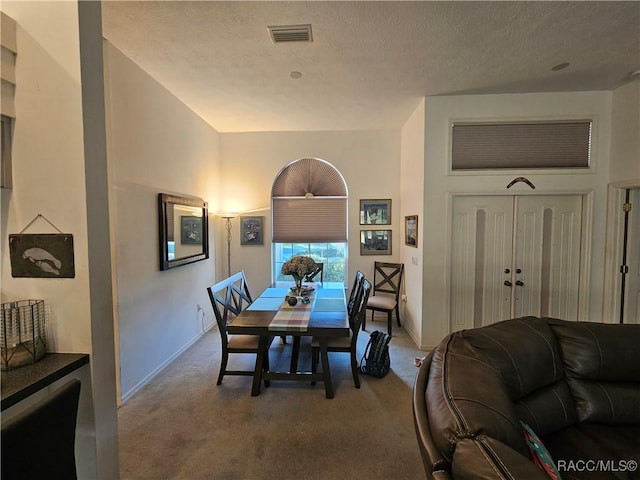 carpeted dining area with a textured ceiling