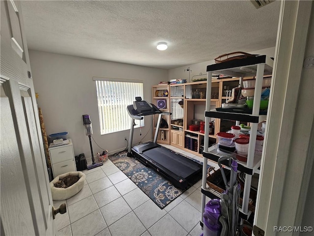 workout area featuring light tile patterned floors and a textured ceiling