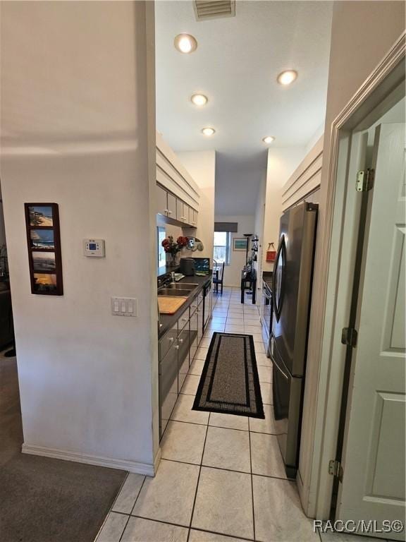 kitchen featuring light tile patterned floors, sink, and stainless steel refrigerator