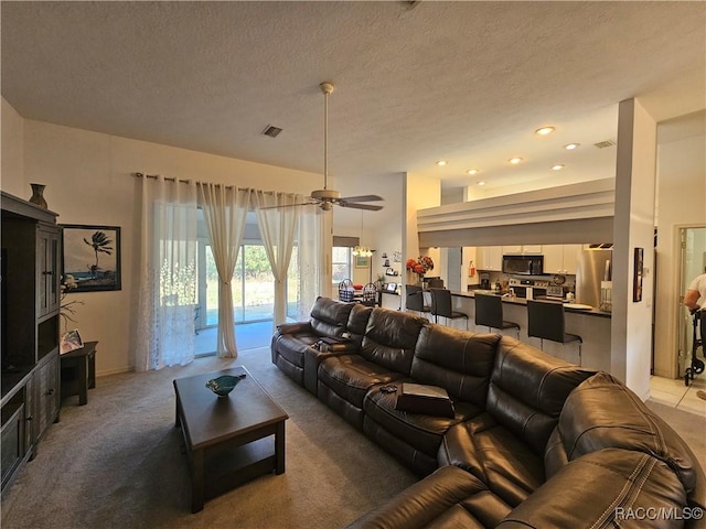 carpeted living room with ceiling fan and a textured ceiling