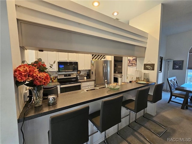 kitchen with stainless steel appliances, white cabinets, a kitchen bar, and kitchen peninsula