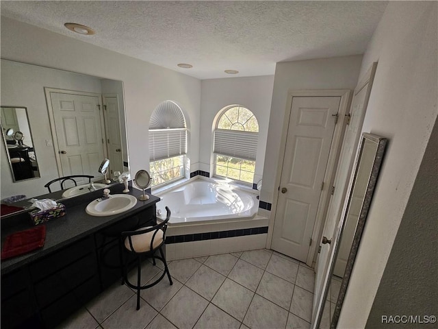 bathroom with tile patterned floors, vanity, a textured ceiling, and tiled tub