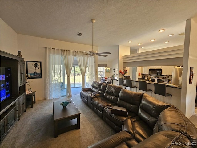 carpeted living room featuring ceiling fan and a textured ceiling