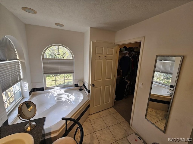 bathroom with tile patterned floors, tiled bath, and a textured ceiling