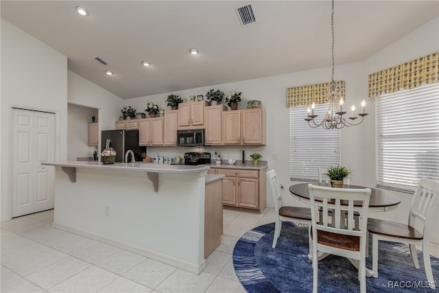 kitchen with a kitchen island with sink, lofted ceiling, stainless steel appliances, and light brown cabinetry