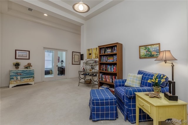 sitting room with carpet flooring, a high ceiling, and french doors