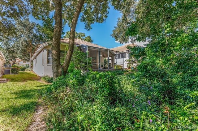 view of side of property with a sunroom and a lawn