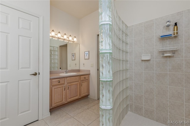 bathroom with tile patterned flooring, vanity, and a tile shower