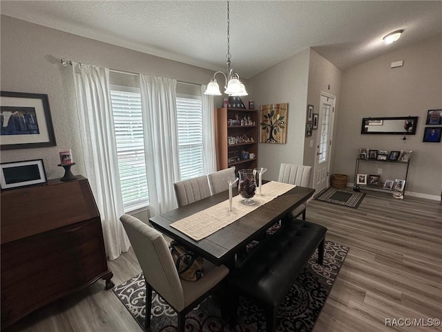 dining space featuring a notable chandelier, hardwood / wood-style flooring, vaulted ceiling, and a textured ceiling