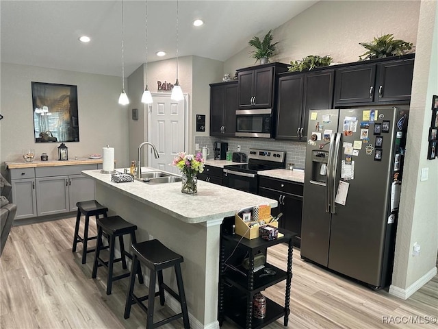 kitchen with a kitchen bar, sink, an island with sink, pendant lighting, and stainless steel appliances