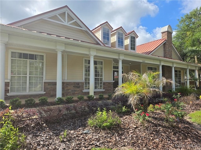 259 Bittern Loop, Inverness, FL 34453 - view of front of house with stone siding, covered porch, a chimney, and metal roof
