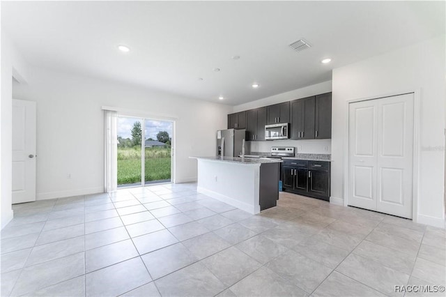 kitchen with stainless steel appliances, a kitchen island with sink, and light tile patterned floors