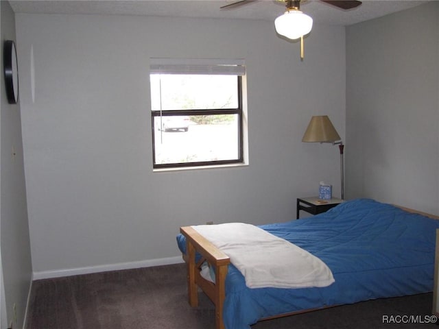 bedroom with a ceiling fan, dark carpet, and baseboards