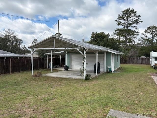 back of property with a garage, a fenced backyard, a patio, and a yard