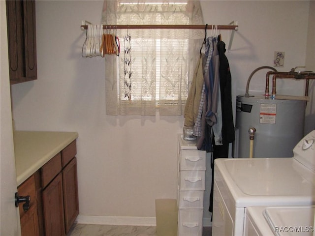 laundry room featuring water heater, washing machine and clothes dryer, cabinet space, and baseboards