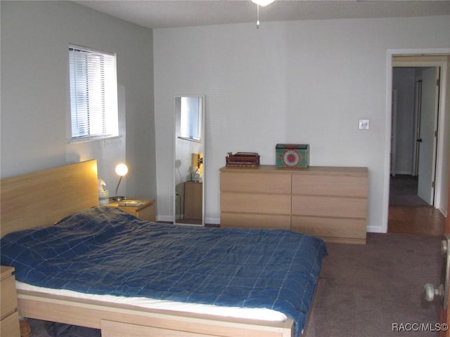 bedroom with dark colored carpet and baseboards