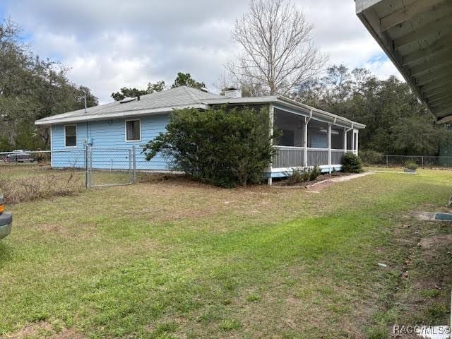 exterior space with a yard, fence, and a sunroom