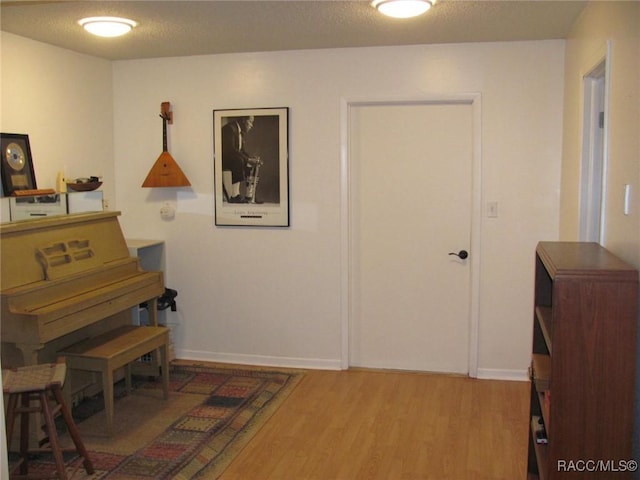 interior space with a textured ceiling, baseboards, and wood finished floors