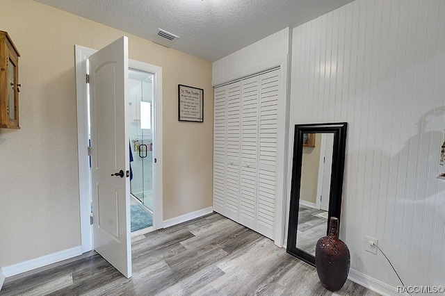 corridor with hardwood / wood-style floors and a textured ceiling