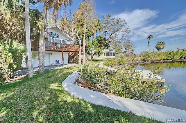 view of yard with a garage and a deck with water view