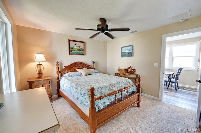 bedroom featuring ceiling fan, light carpet, and a textured ceiling